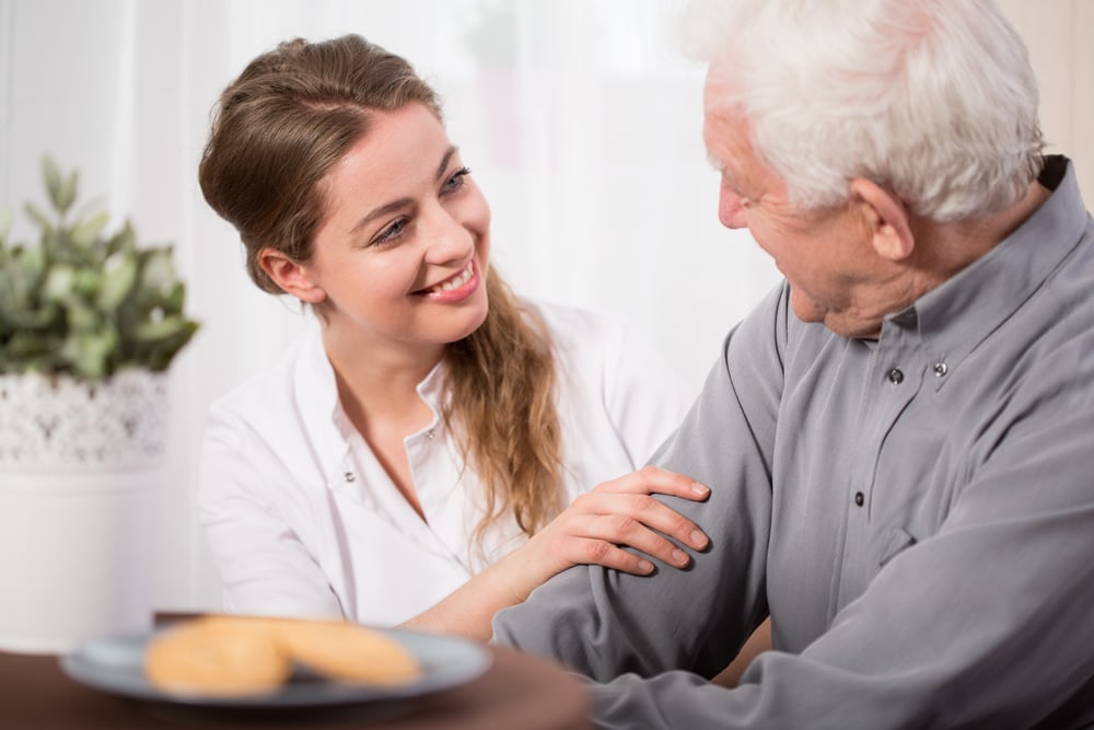 Aide with male patient in home smiling