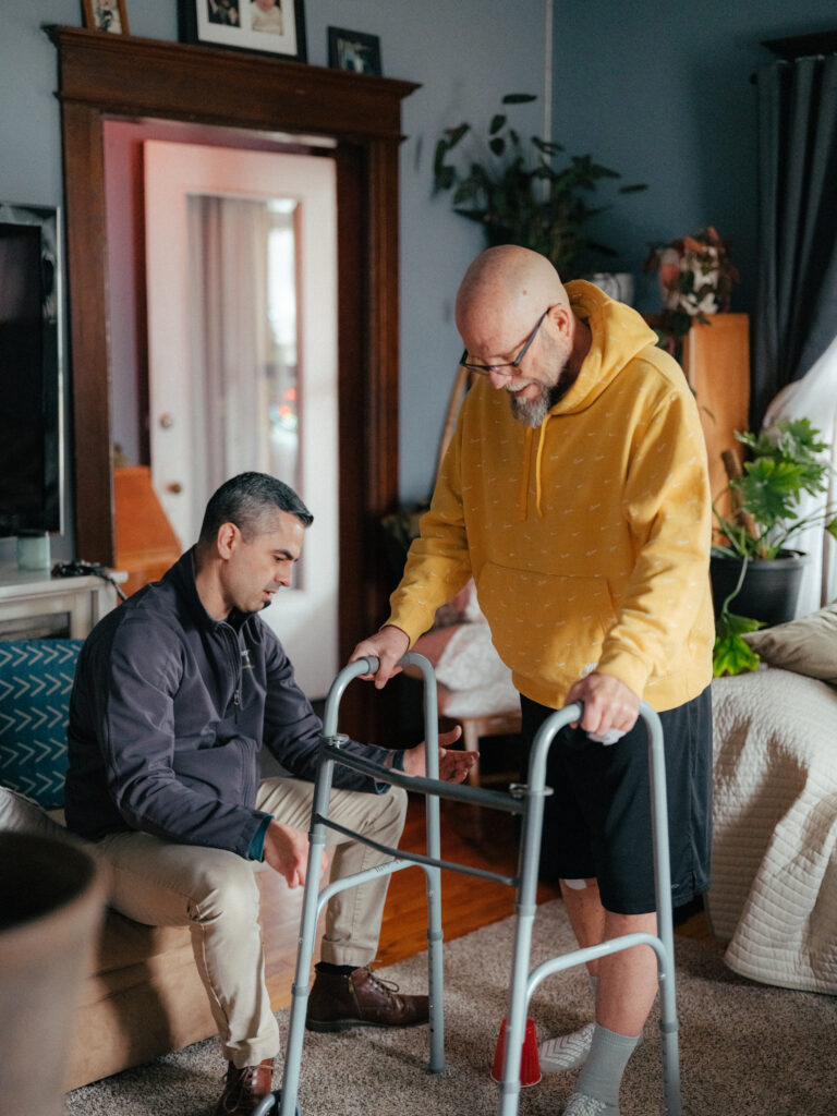 Caregiver assisting elderly patient with walker at home